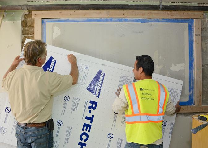 Tom Bilisoly (left), Spectra Company supervisor and senior artisan, and Damien Mortino, Spectra Company craftsman and artisan, prepare to encase and protect the historic Muroc Manor signature wall from any debris during the wall’s extraction process. The signature wall potentially holds hundreds of signatures dating from the early 1940s to the 1960s. (U.S. Air Force photo by Jet Fabara)