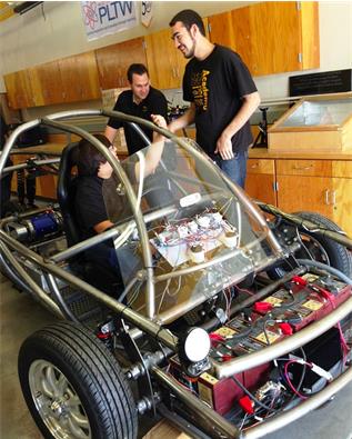 Nicholai Pleitez (left), 17; James Stockdale (center), Digital Design & Engineering Academy coordinator of Knight High School; and Kyle Barrett, 17, discuss their finished electric car project on Jan. 22. (Photo by Jim E. Winburn)